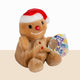 Plush gingerbread bear with a Santa hat and red nose, holding a Palm Pals tag on a beige background.