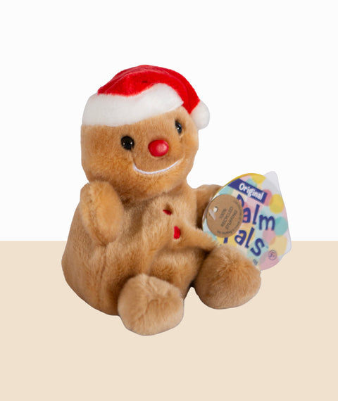 Plush gingerbread bear with a Santa hat and red nose, holding a Palm Pals tag on a beige background.
